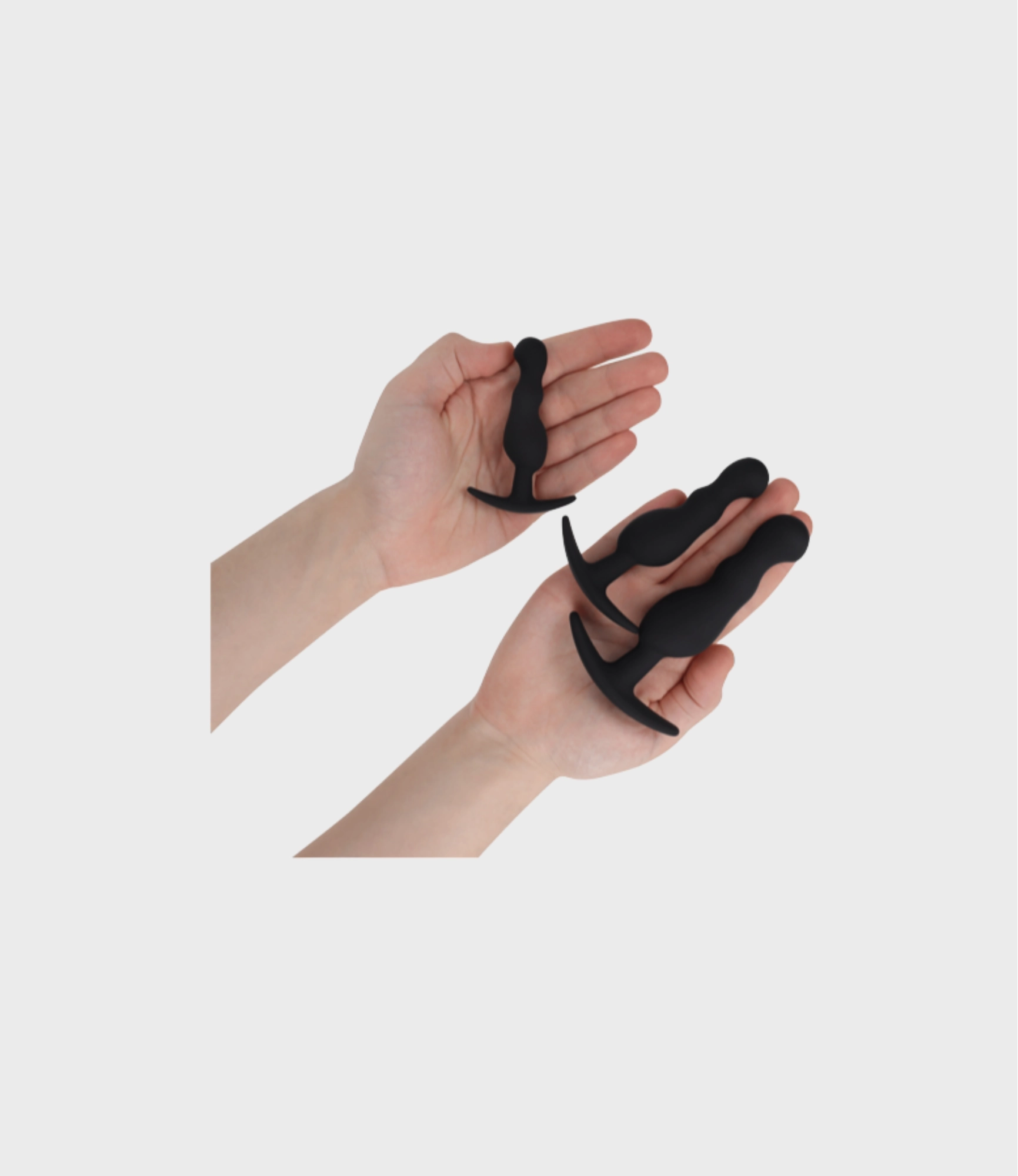 Manos sujetando los tres plugs anales del set Addicted Toys
